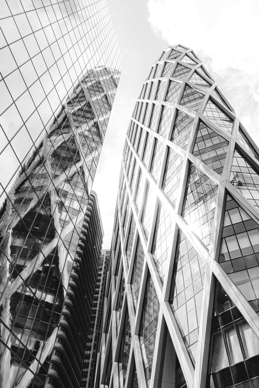 A low-angle shot of modern glass skyscrapers reflecting sunlight, symbolising corporate growth and financial success.