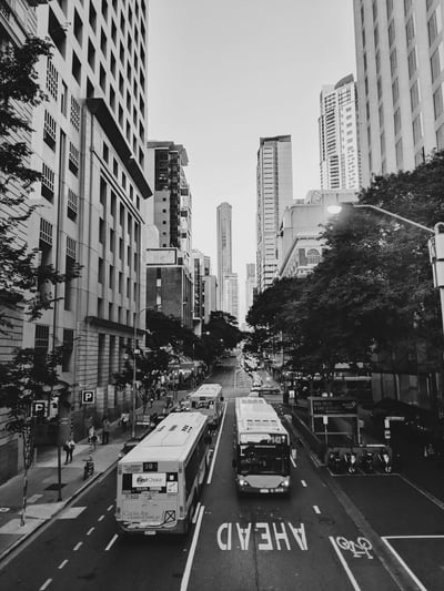 People Walking Near Busy Street Beside Different Vehicles on Road Surrounded With High-rise Buildings